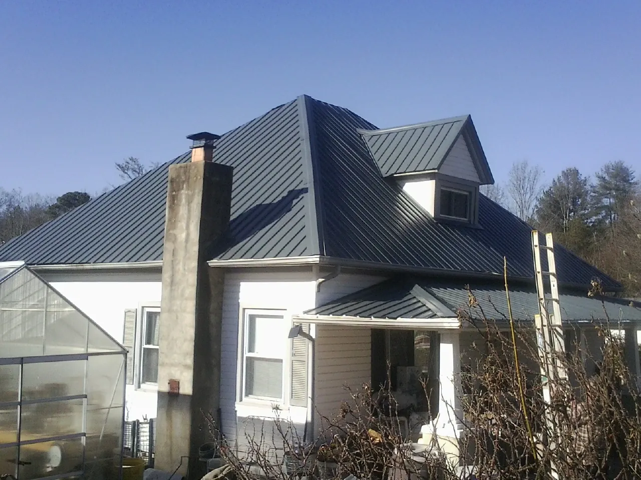 Dark blue standing seam metal roof on a white farmhouse with dormer — Slate & Tile Roof Repair by Roofing Brothers in Scandinavia