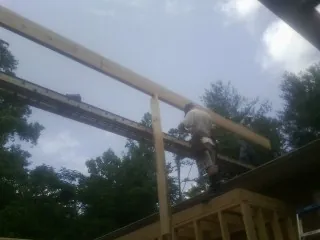 Carpenter setting a ridge beam over a new addition frame — Ice Dam Removal by Roofing Brothers in Scandinavia