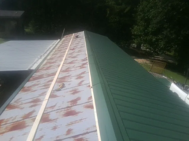 Old rusted panels beside newly installed green metal roofing — Wind Damage Roof Repair by Roofing Brothers in Scandinavia