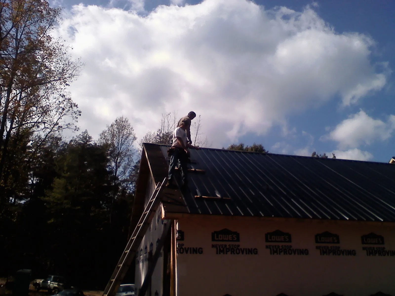 Roofer fastening dark metal panels high against a cloudy sky, from a Roof Inspection job in Scandinavia
