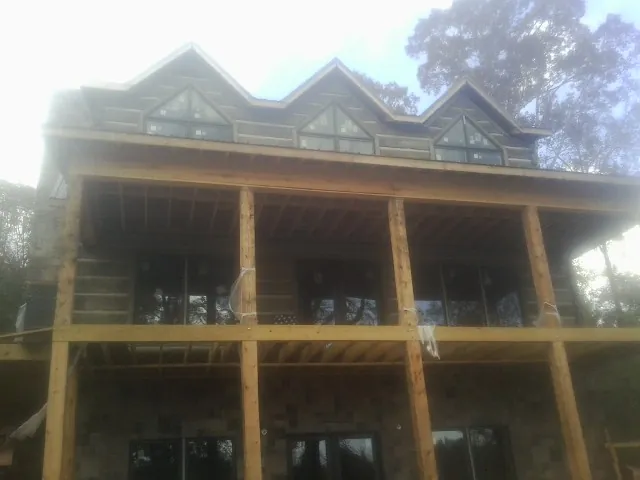 Dormers and porch framing on a large log home under construction — Roof Coating work by our crew in Scandinavia