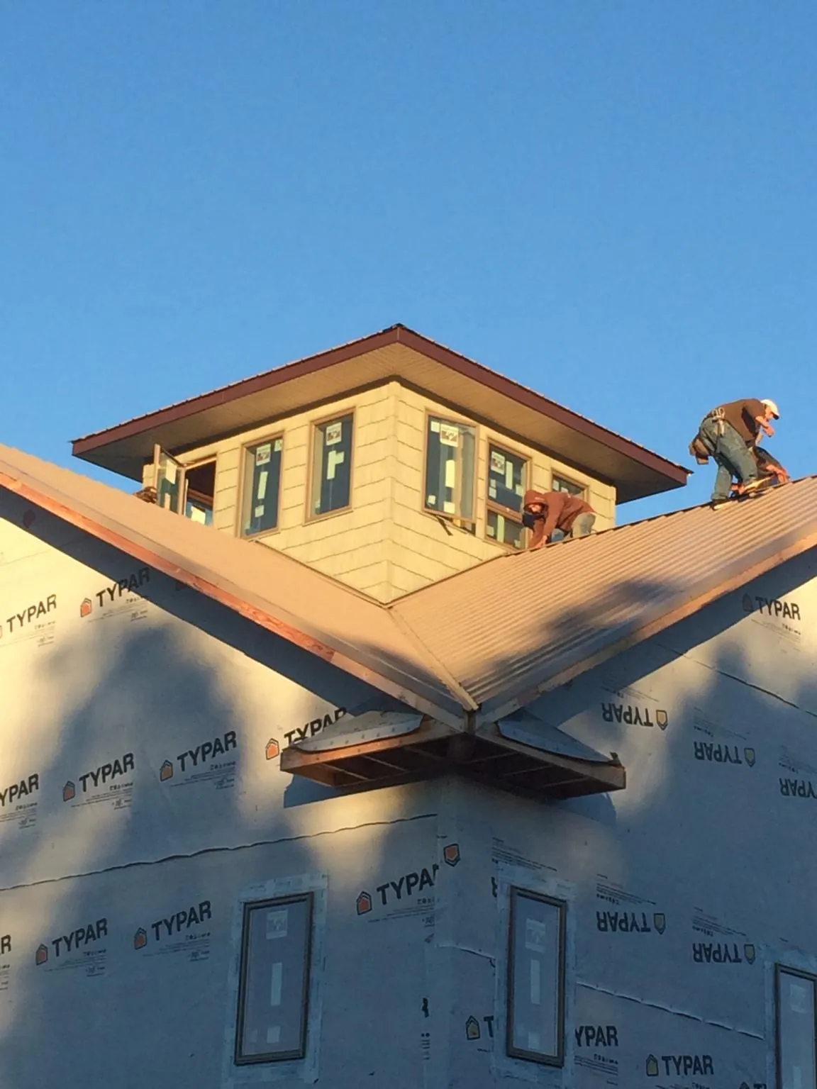 Roofers working around a rooftop cupola on a new metal roof at sunset — Roof Waterproofing in Scandinavia by Roofing Brothers